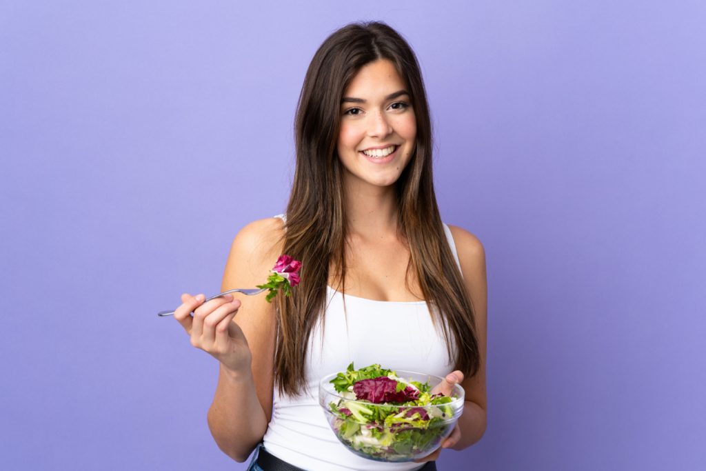Mulher segurando uma salada, simbolizando alimentação saudável para mais energia e foco.