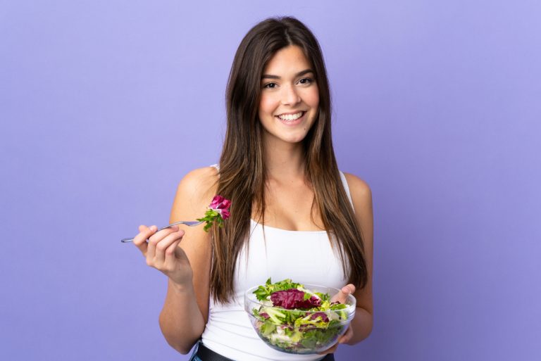 Mulher segurando uma salada, simbolizando alimentação saudável para mais energia e foco.