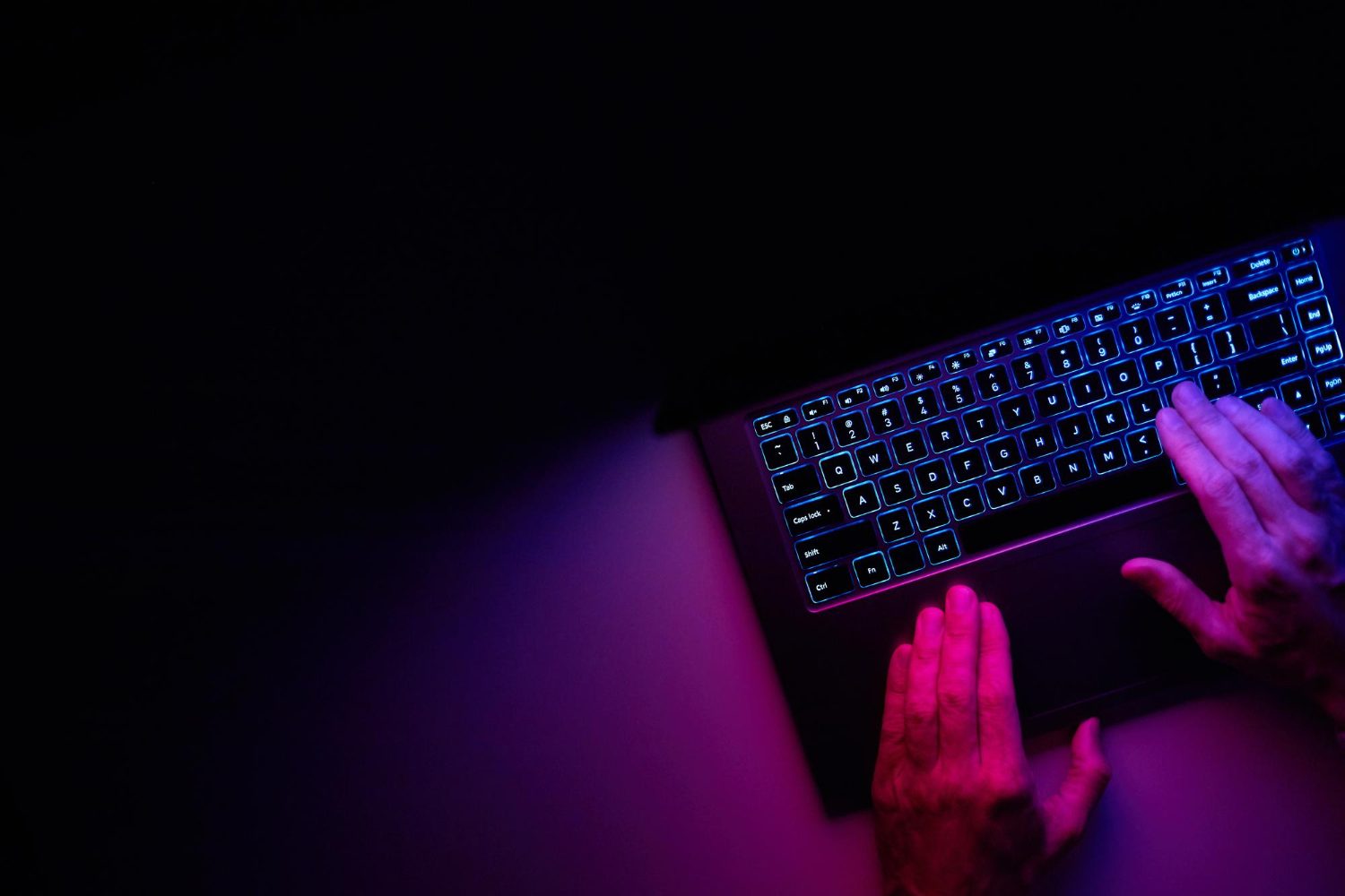 Pessoa utilizando notebook com iluminação neon para gestão ágil de projetos de software